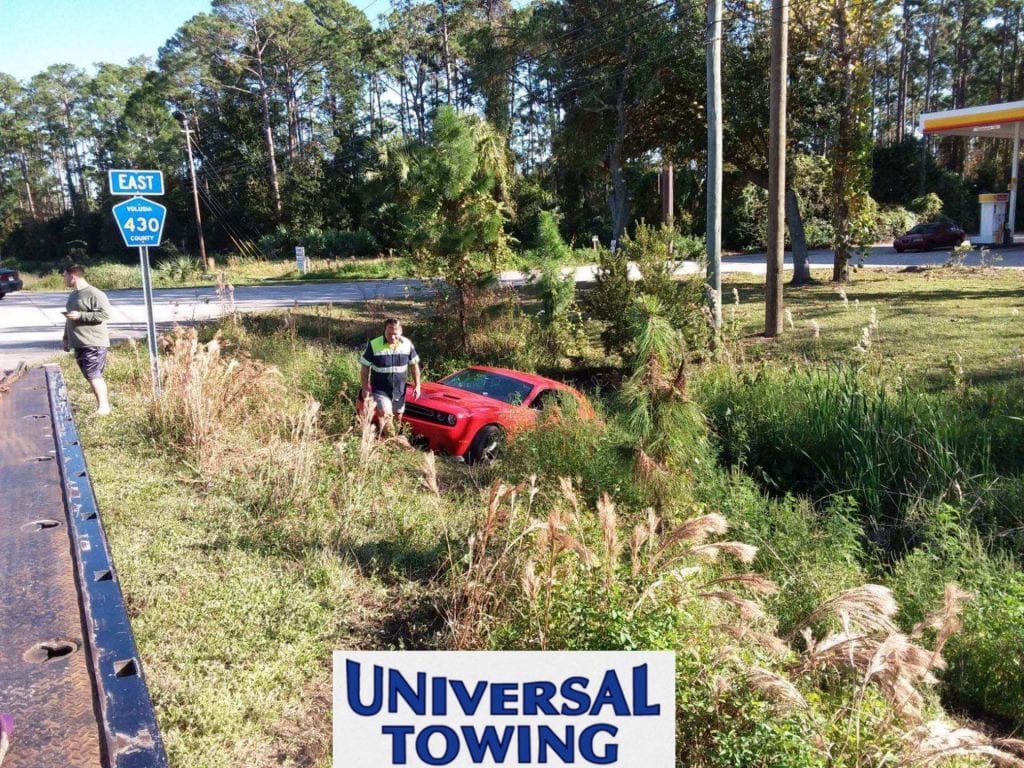 universal towing Daytona provides towing services for red Dodge Challenger in retention pond